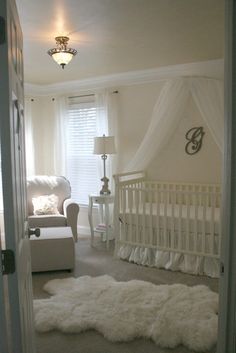 a baby's room with a white crib, chair and rug on the floor