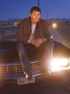 a man sitting on the hood of a car