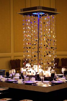 a dining room table is set up with place settings and candles in front of the chandelier