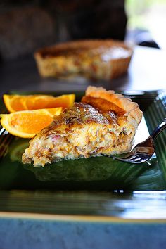 a slice of quiche on a green plate with oranges