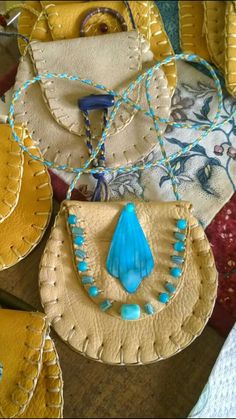 several purses are sitting on the table together, some have blue beads and one is yellow