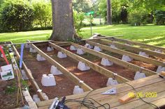 an outdoor garden area with wooden boards and plastic bags on the ground, surrounded by trees