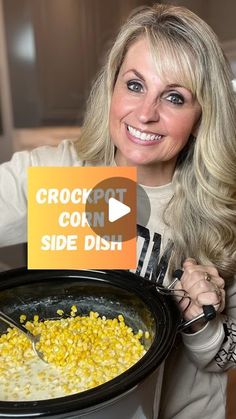 a woman holding a crock pot with corn on the side dish in front of her