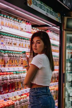 a woman standing in front of a display of drinks and condiments at a grocery store