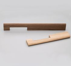 a pair of wooden handles on a white surface with a gray background and one is made from wood