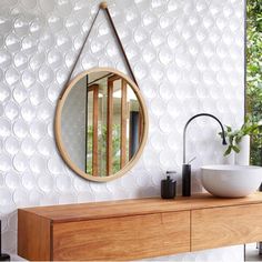 a bathroom with a sink, mirror and vase on the counter next to wallpaper