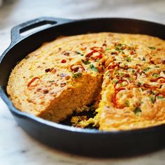 a skillet filled with cornbread and vegetables on top of a marble countertop