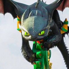 a close up of a dragon statue with yellow eyes and green wings on it's head