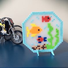 a toy motorcycle next to a plastic beaded sign with an image of a fish on it