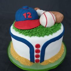 a cake decorated with baseball, glove and ball on top of grass covered plate in front of black background