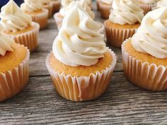 several cupcakes with white frosting and bananas in the background on a piece of parchment paper