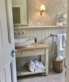 a bathroom with a sink, mirror and towel rack next to the door that is open