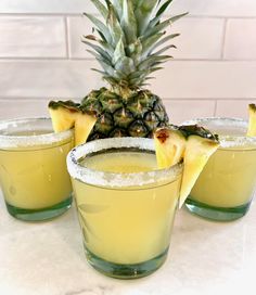 three glasses filled with pineapple punch sitting on top of a table