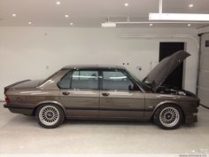 a car with its hood open sitting in a garage next to a door that is opened