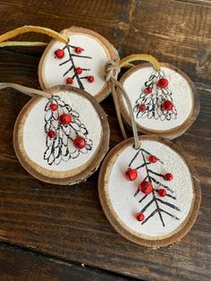 four wooden ornaments with red beads on them sitting on top of a wood table next to a string