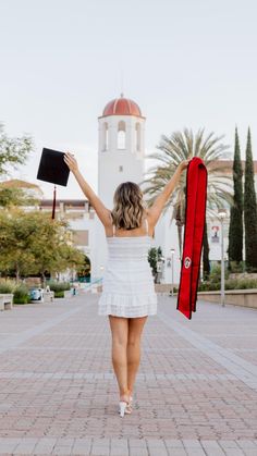 a woman is walking down the street with her graduation cap and gown in hand,