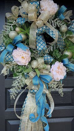 a blue and gold wreath with flowers hanging on a front door ornament for the holiday season