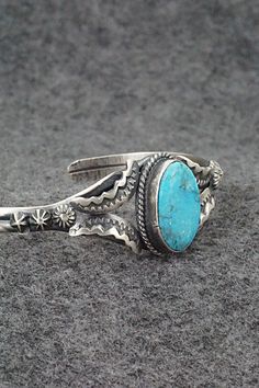 This beautiful natural Kingman turquoise and sterling silver bracelet was made by Navajo silversmith Gilbert Tom. The back is signed Gilbert Tom and stamped sterling.Size: 5 1/2" (will fit up to a 6 5/8" wrist)Gap: 1 1/8"Width: 7/8"Cuff Width: 1/4"Free shipping on all orders! We ship with USPS and always include tracking. All orders ship within a day of payment.Returns are accepted up to 30 days after you receive your order. Just send us a message. Our shop offers cash back or store credit. The Stamped Sterling Silver Bracelet In Turquoise, Blue Southwestern Style Bracelets Stamped 925, Stamped Turquoise Sterling Silver Bracelet, Southwestern Style Turquoise Bracelet Stamped 925, Vintage Turquoise Sterling Silver Bracelets, Turquoise Sterling Silver Bracelet With Patina, Sterling Silver Turquoise Stamped Bracelet, Adjustable Turquoise Sterling Silver Bracelet In Southwestern Style, Handmade Southwestern Sterling Silver Bracelet