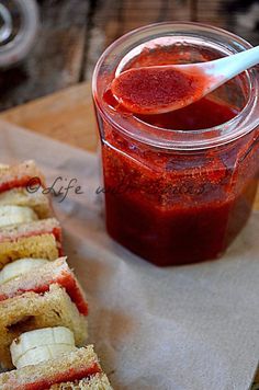 a sandwich cut in half sitting on top of a napkin next to a jar of jelly