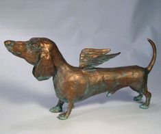 a bronze statue of a dog with wings on it's head and tail, standing upright