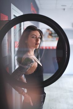 a woman with tattoos is looking through a magnifying glass to see herself in the mirror