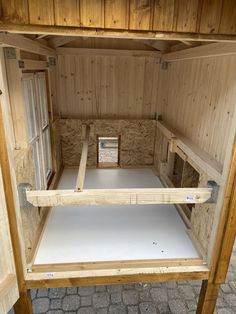 the inside of a small wooden building with white sheets on the floor and two windows