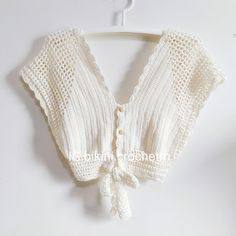 a white knitted top hanging on a hanger