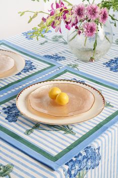 two plates with lemons on them are sitting on a blue and white tablecloth