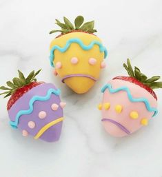 three decorated strawberries sitting on top of a white counter