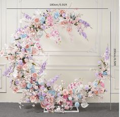 an arrangement of flowers arranged in the shape of a wreath on a wall with measurements