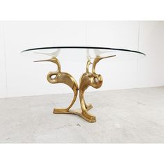 a glass and brass coffee table with two birds on it's legs, in the shape of an elephant