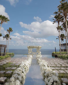 an outdoor ceremony setup with white flowers and greenery on the aisle, overlooking the ocean