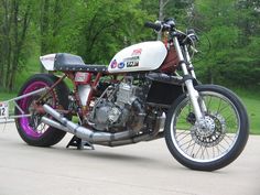 a white and red motorcycle parked on top of a street next to trees in the background