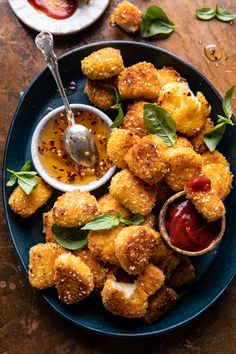 a blue plate topped with fried food next to a bowl of ketchup and sauce