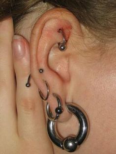 a close up of a person with ear piercings on their ears and behind the ear