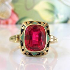 a close up of a ring with a red stone