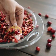 a person picking up cranberries from a bowl