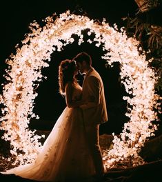 a bride and groom standing in front of a lighted archway