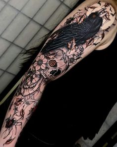 a black bird sitting on top of a woman's arm with flowers around it