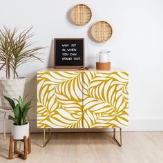 a yellow and white cabinet with some plants on it next to a chalkboard that says why fit in when you stand out