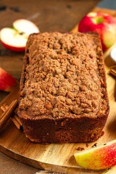 a loaf of bread sitting on top of a wooden cutting board next to an apple