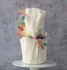 a three tiered white cake with colorful flowers on top