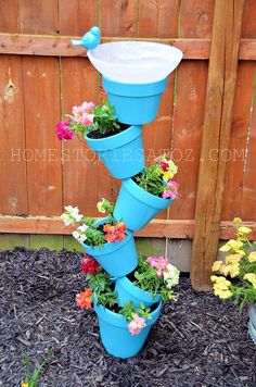 a blue birdbath with flowers growing out of it's bottom and on top