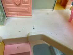 there is a toy kitchen with pink and yellow furniture on the floor, as well as other toys