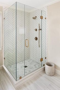 a walk in shower sitting next to a white wall and wooden floor with gold accents