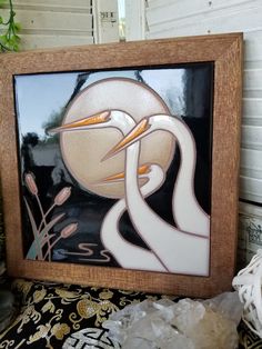 two white birds sitting on top of a table next to a vase with flowers in it