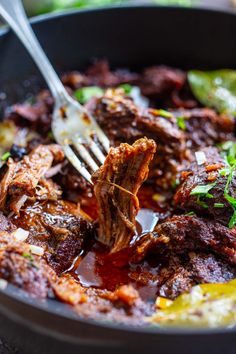 a skillet filled with meat and vegetables being stirred with a fork to eat it