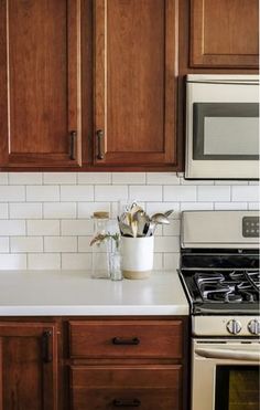 a kitchen with wooden cabinets and white counter tops, an oven and microwave in the corner