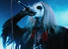 a woman with long hair and makeup on holding a microphone in front of her face