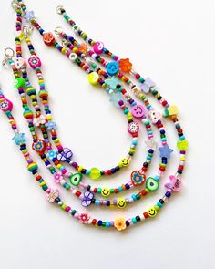 multicolored beaded necklace with charms on white background, close up view from above